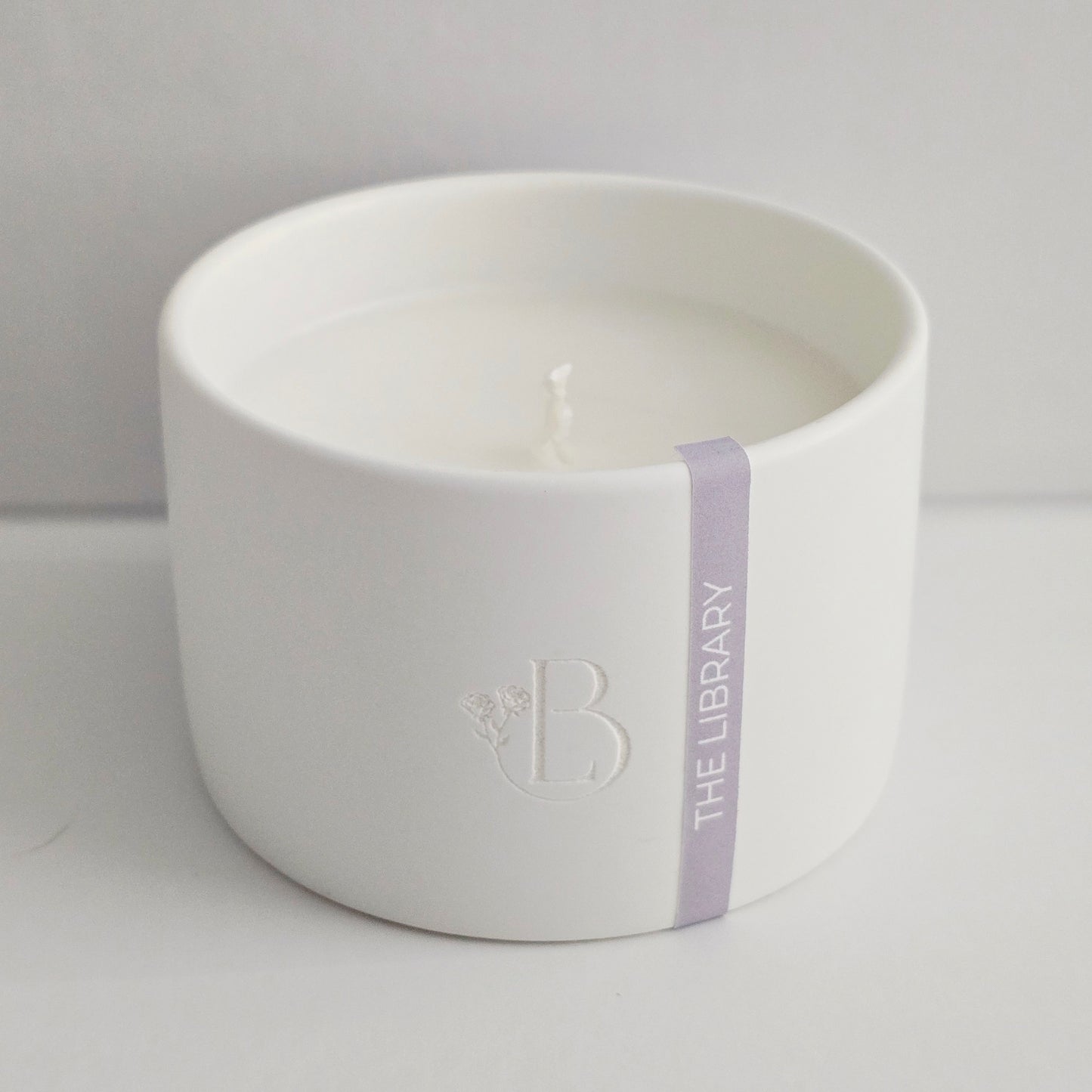 White ceramic bowl with a candle inside on a light gray background