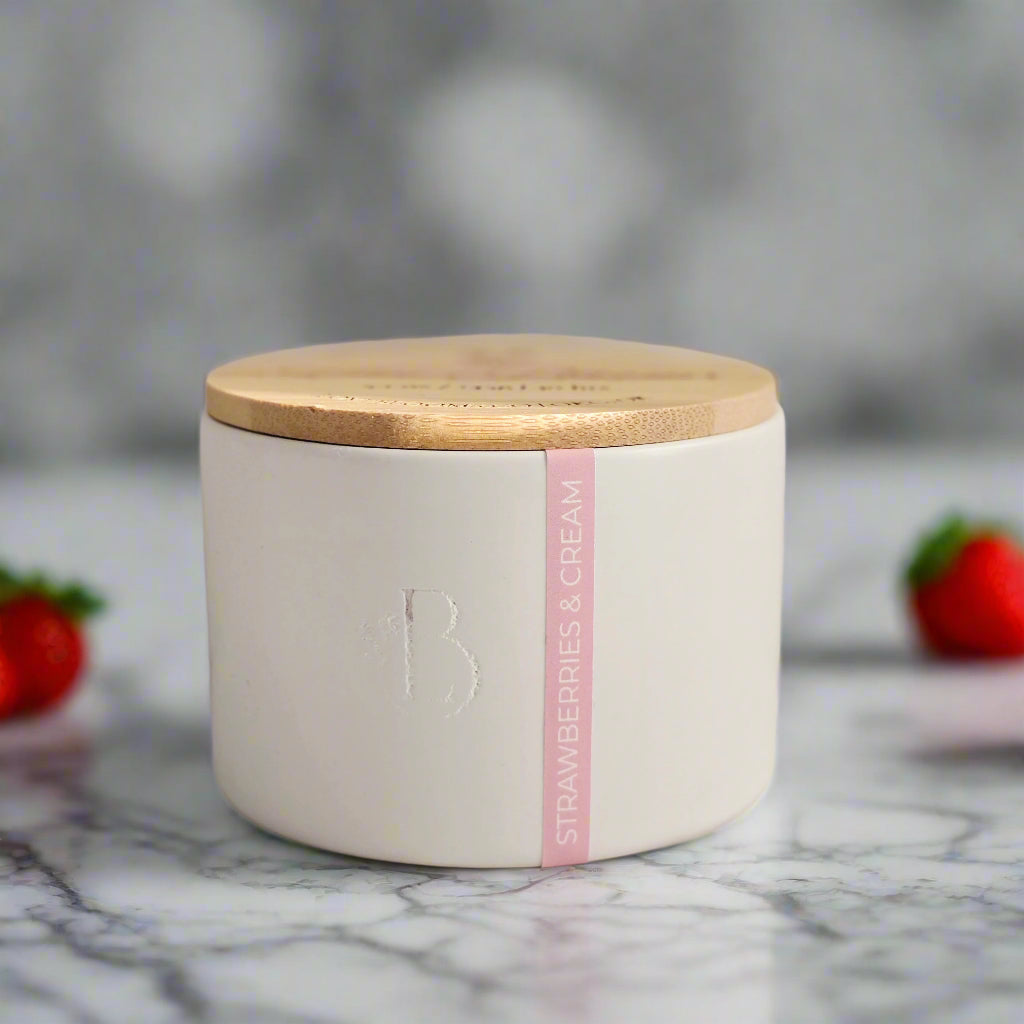 White candle jar with wooden lid on a light gray background