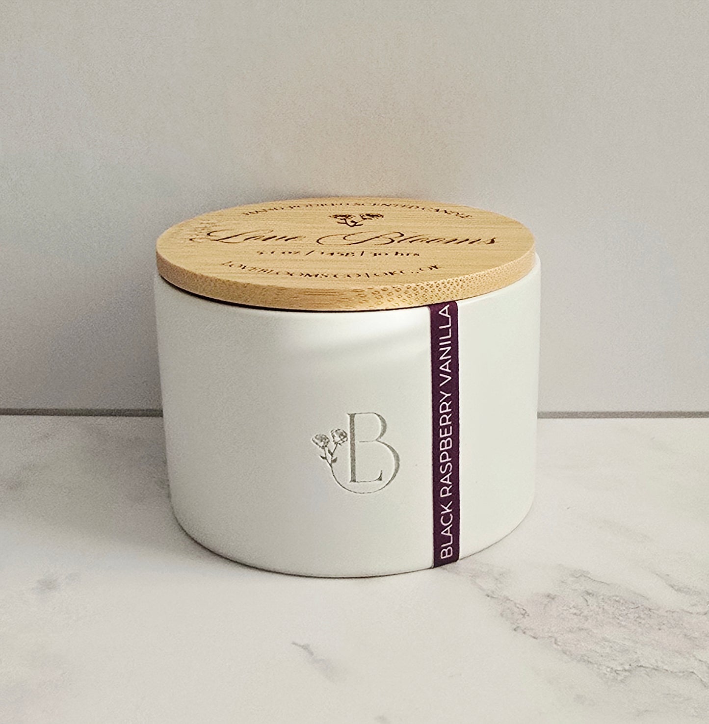 White candle jar with wooden lid on a marble surface