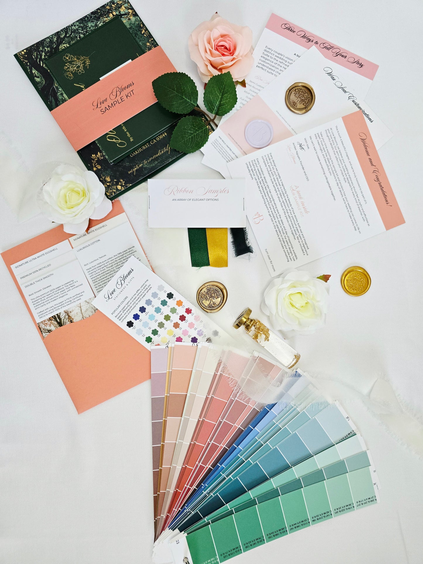 Color swatches, stationery items, and flowers on a white surface