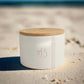 White storage jar with wooden lid on a light surface