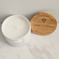 White candle in a container with a wooden lid on a marble surface