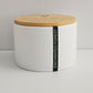 White candle jar with wooden lid and 'Enchanted Forest' label on a light gray background