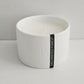White candle in a bowl with 'Enchanted Forest' label on a light gray background