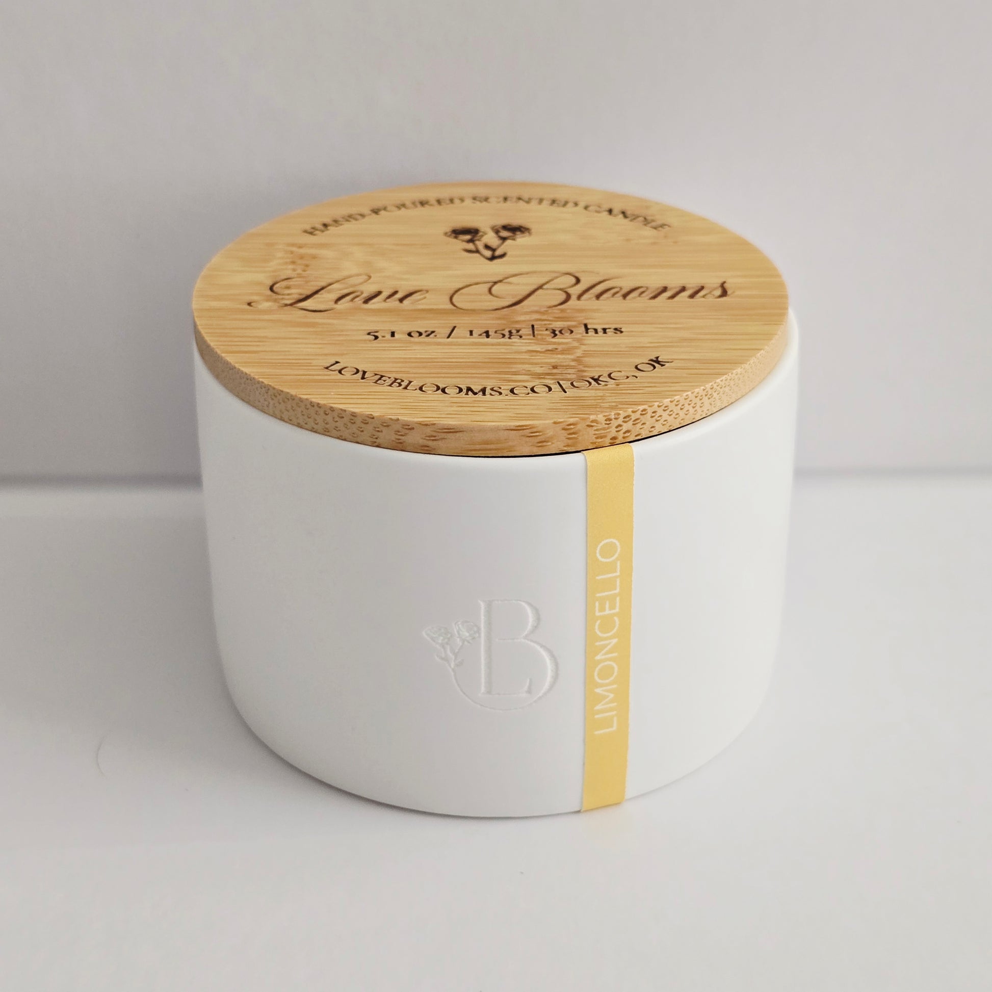White candle jar with wooden lid on a light gray background