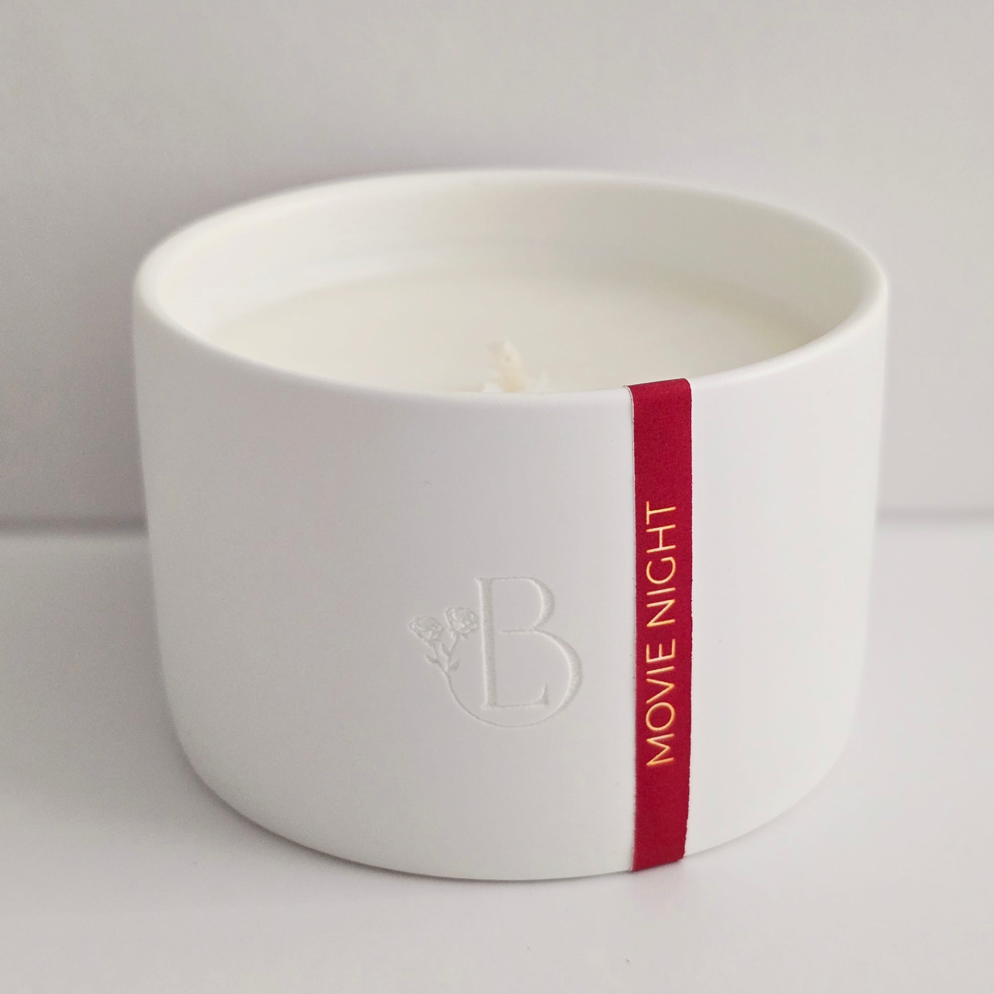 White candle with a red band and 'Movie Night' text on a light red background