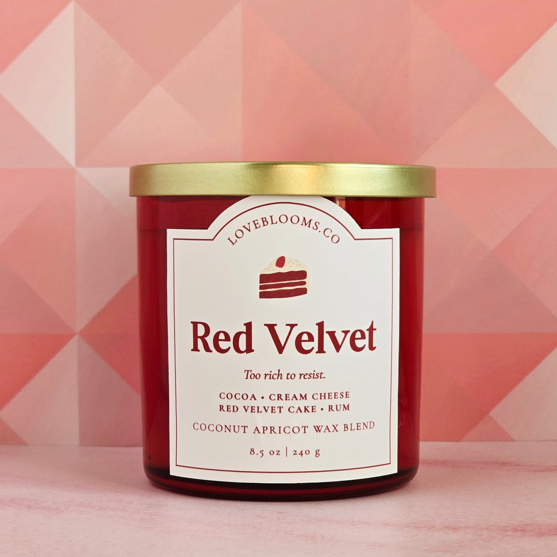 Red velvet candle with gold lid on a pink geometric patterned background