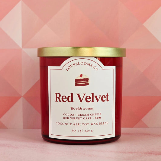 Red velvet candle with gold lid on a pink geometric patterned background