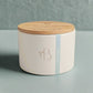 White ceramic jar with wooden lid on a light surface
