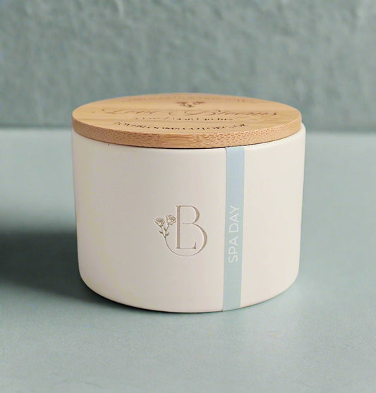 White ceramic jar with wooden lid on a light surface