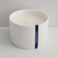 White candle in a ceramic holder with 'Stargazer' text on a light gray background