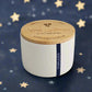 White candle with a wooden lid on a light gray background