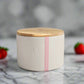 White candle jar with wooden lid on a light gray background