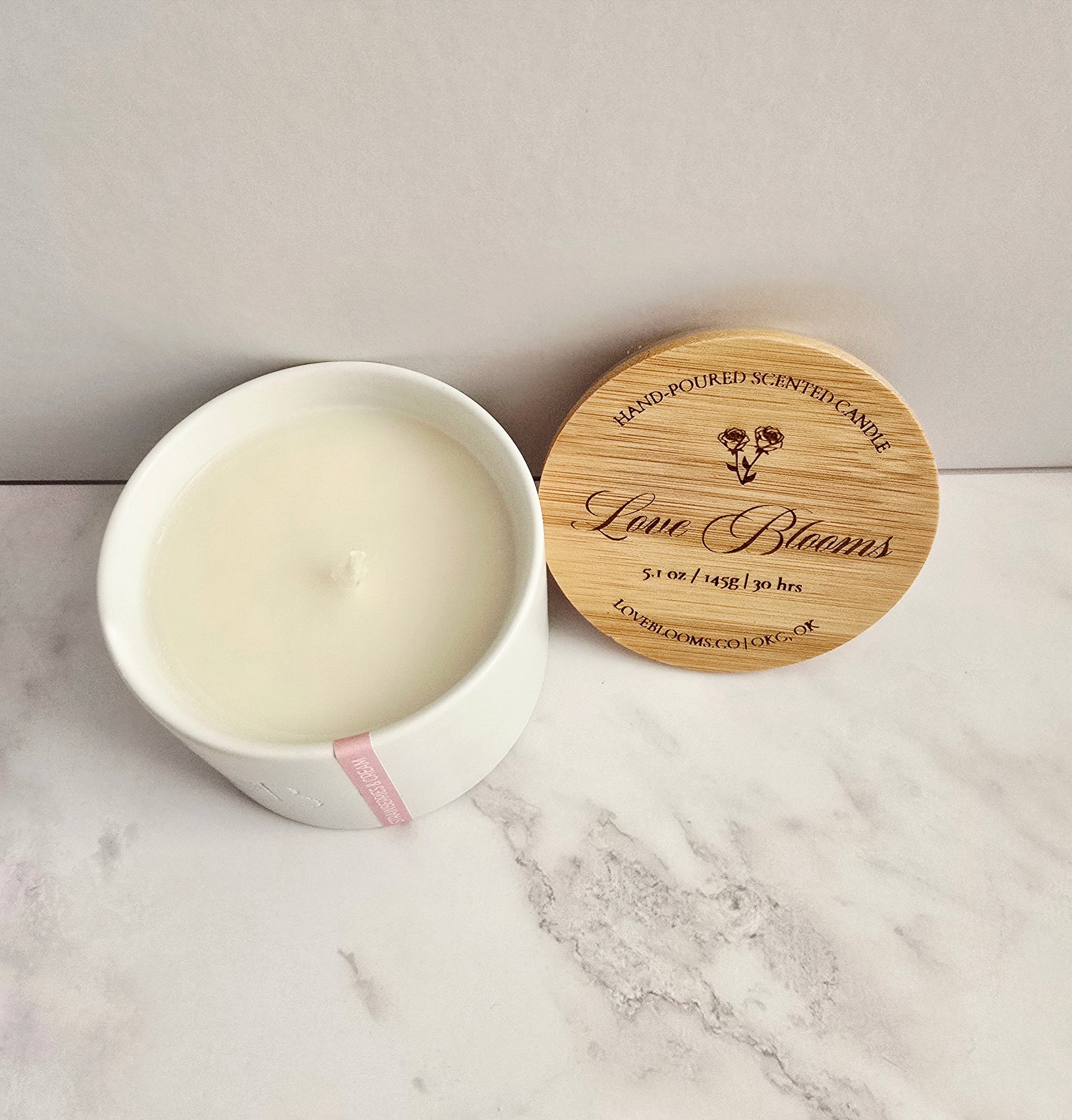 Candle in a white container with a wooden lid on a marble surface