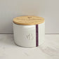 White candle jar with wooden lid on a marble surface