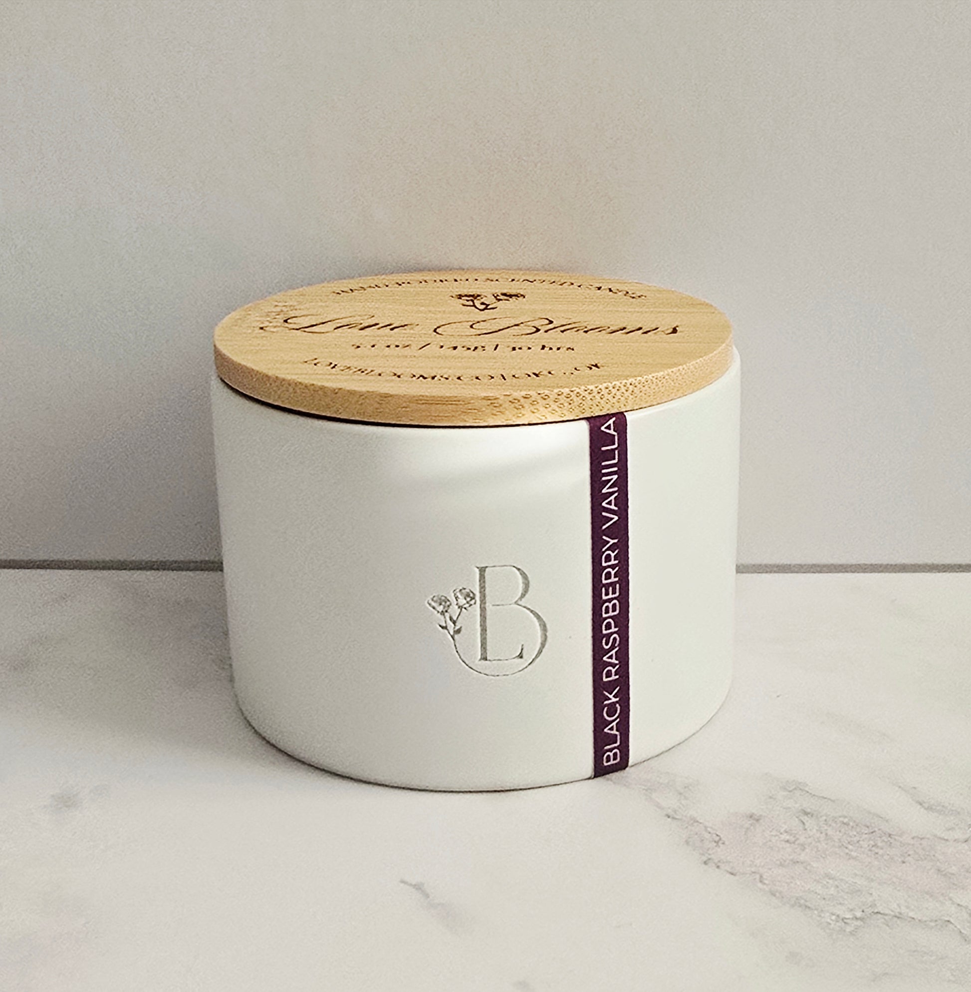 White candle jar with wooden lid on a marble surface