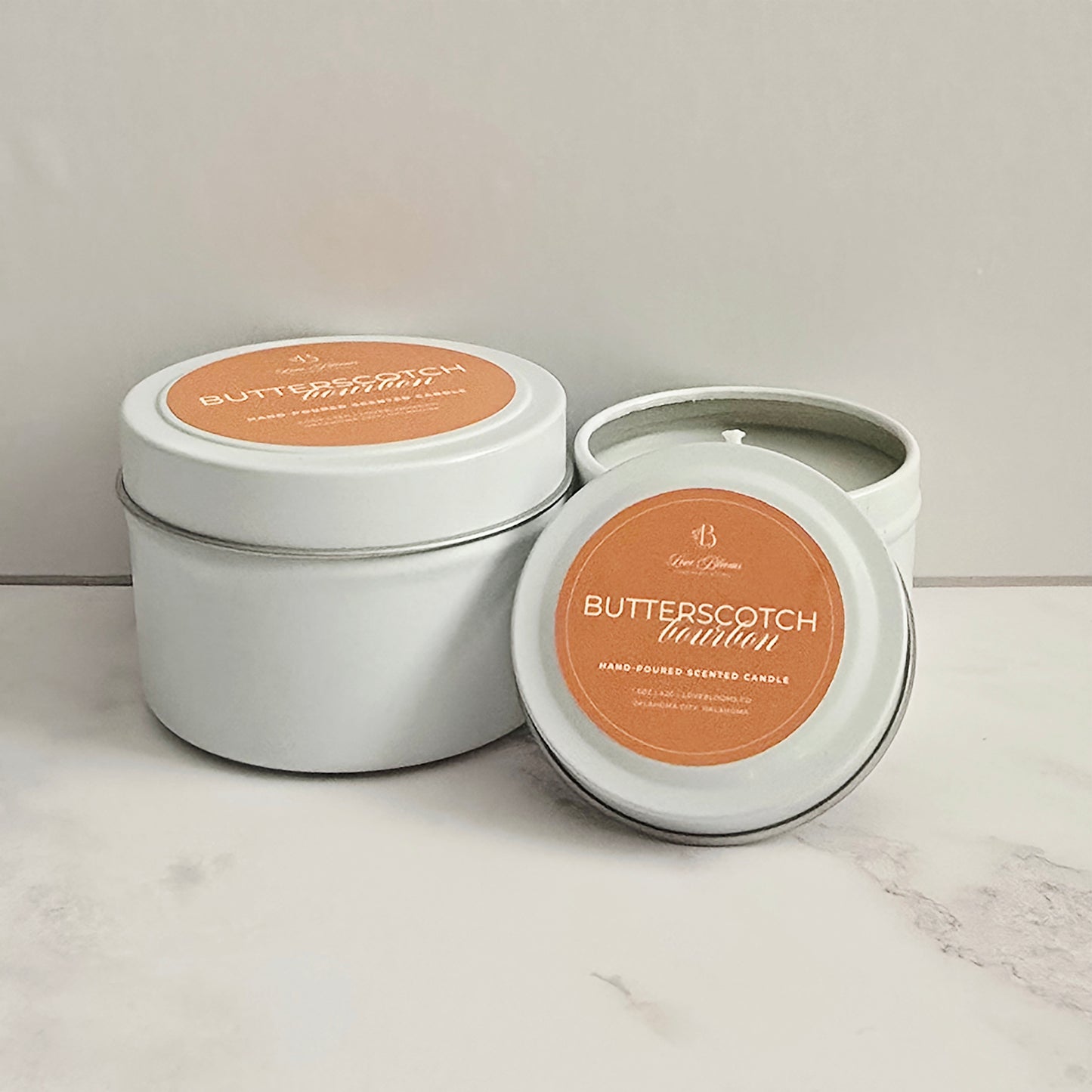 Butterscotch scented candle in a white tin with a matching lid on a light background