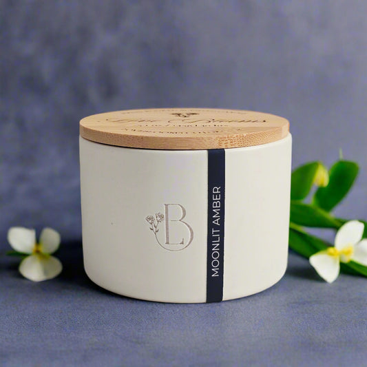 White candle jar with wooden lid on a marble surface