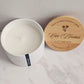 Candle in a white container with a wooden lid on a marble surface