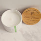 White candle container with wooden lid on a marble surface