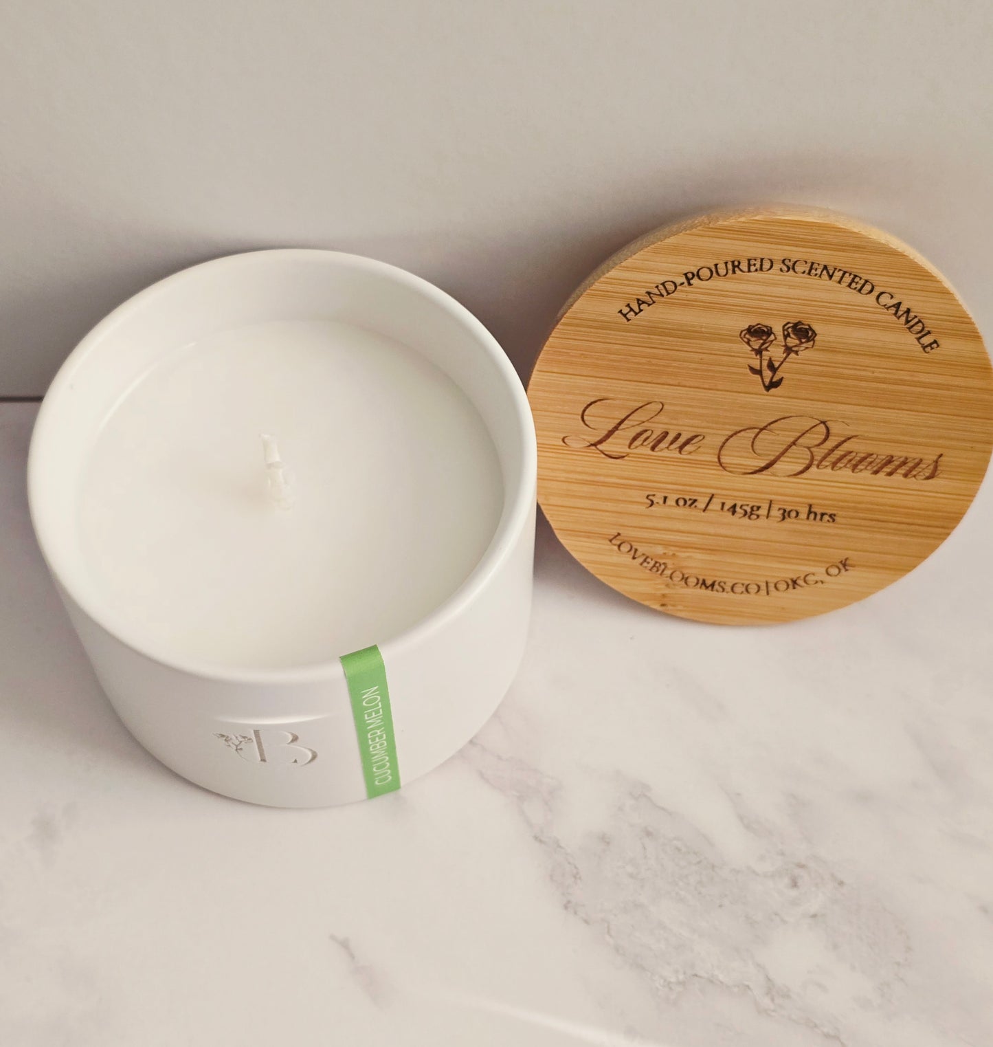 White candle container with wooden lid on a marble surface