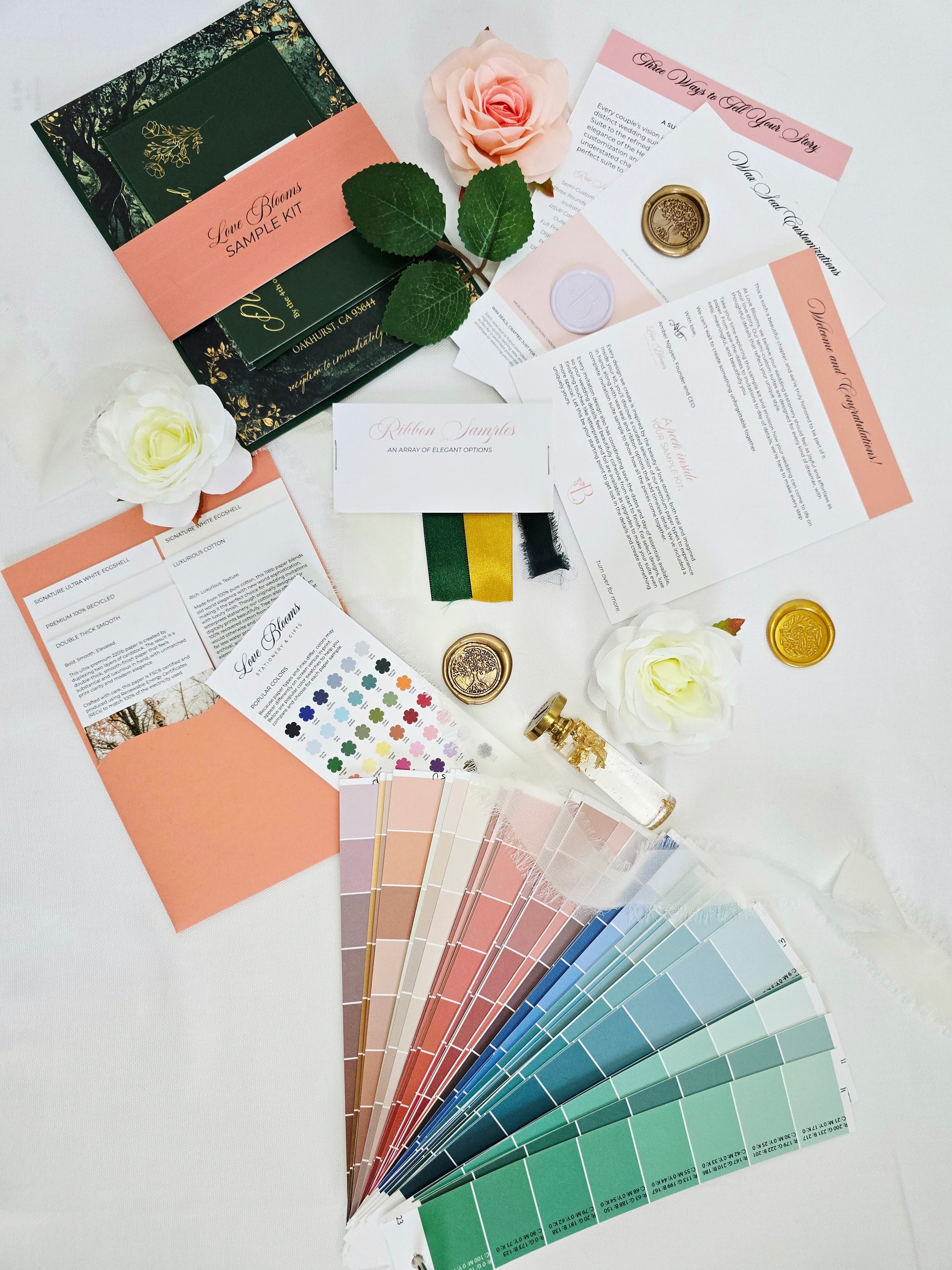 Color swatches, stationery items, and flowers on a white surface